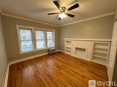 A room with a ceiling fan and wooden flooring.