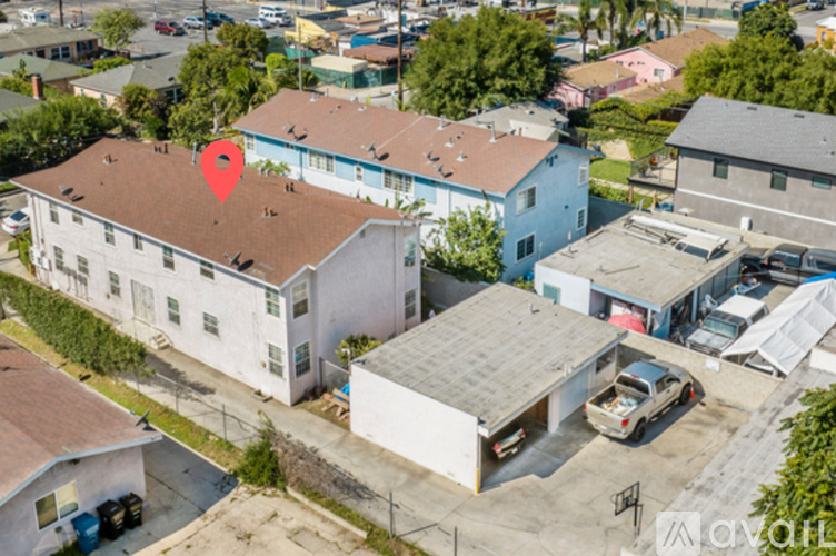 A red pin marks a location on a white building with a brown roof.