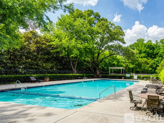 A large outdoor swimming pool surrounded by trees and lounge chairs.