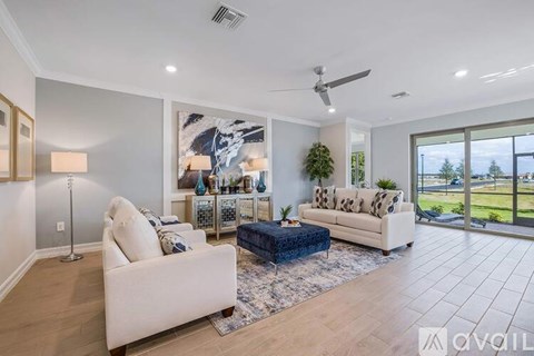 A living room with a white couch and a blue ottoman.