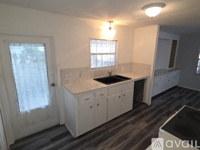 A kitchen with white cabinets and a window above the sink.