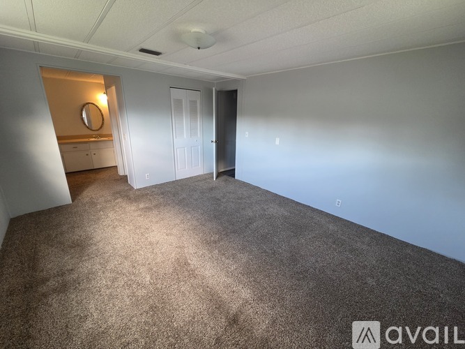A carpeted room with a door and a mirror on the wall.