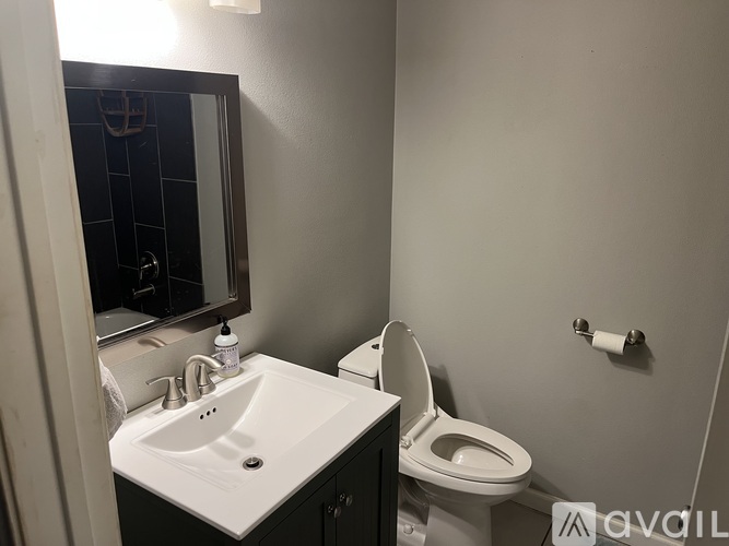 A bathroom with a toilet, sink, and mirror.