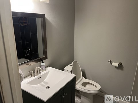 A bathroom with a toilet, sink, and mirror.