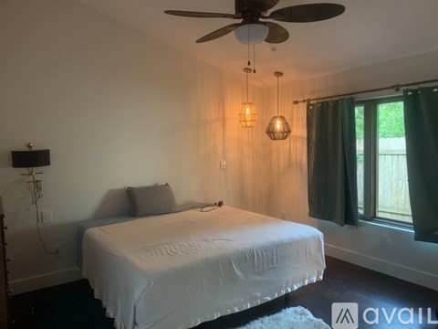 A bedroom with a white bed and a ceiling fan.