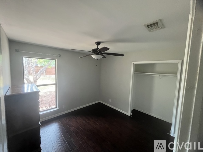 A room with a ceiling fan and a sliding glass door.