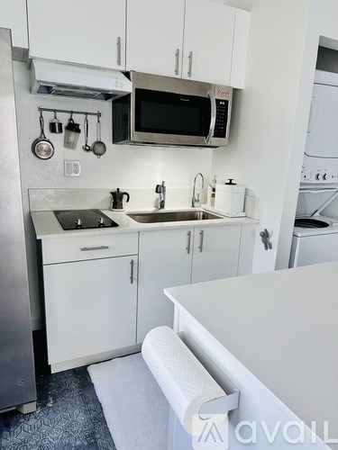 A kitchen with white cabinets and a stainless steel refrigerator.