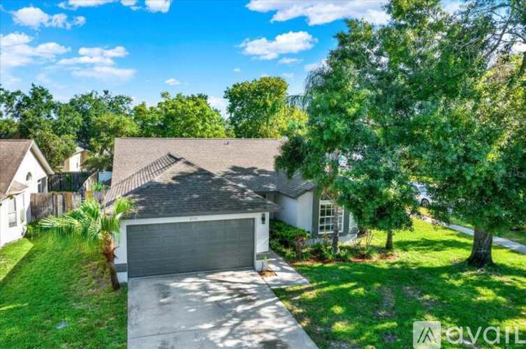 A house with a garage is surrounded by greenery.