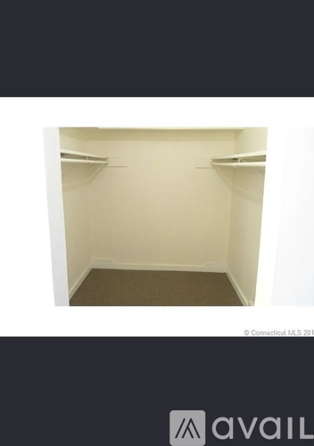 A small, empty room with a carpeted floor and two shelves on the wall.