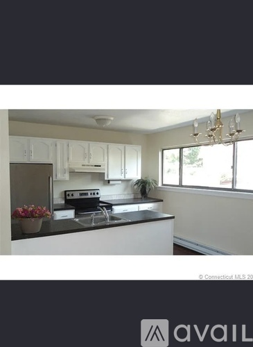 A kitchen with white cabinets and a black countertop.