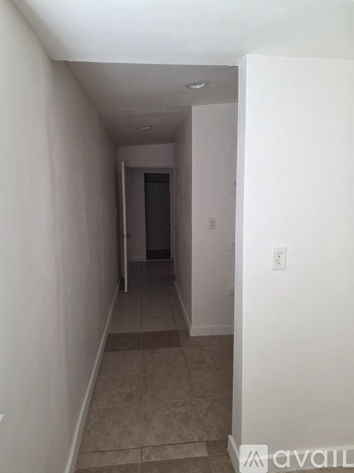 A hallway with a door at the end and a tiled floor.