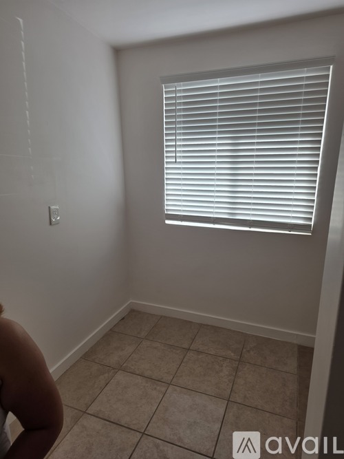 A room with a window covered in white blinds.