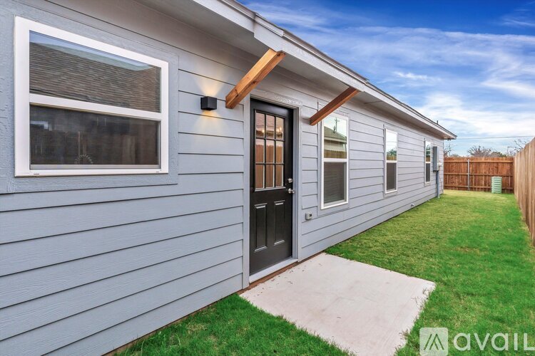 A house with a grey exterior and a black door is available for rent.