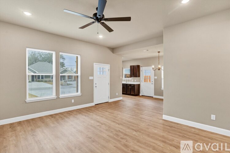 A spacious room with a ceiling fan and hardwood flooring.