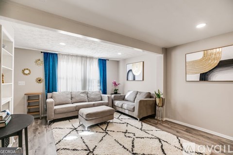 A living room with a grey sofa set and a black and white rug.