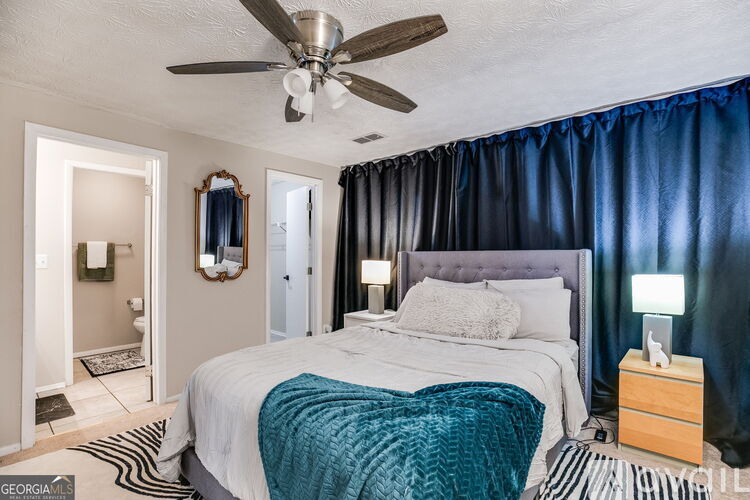 A bedroom with a bed, a ceiling fan, and a nightstand.