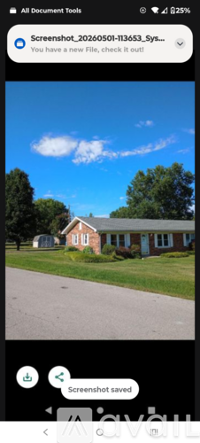 A red brick house with a white door and windows is in front of a grassy area and trees.