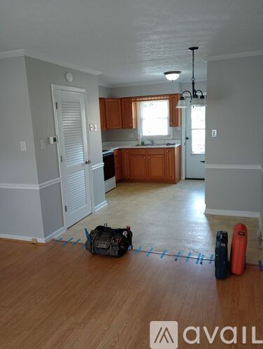 A room with wooden floors and a kitchen area in the background.