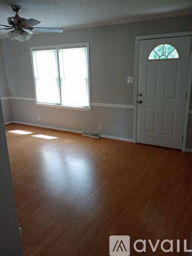 A room with a white door and a window with sunlight coming through.
