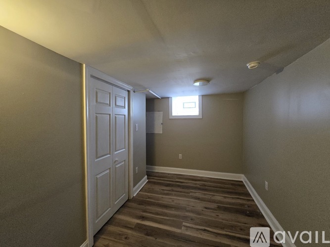 A room with a wooden floor and a door on the left side.