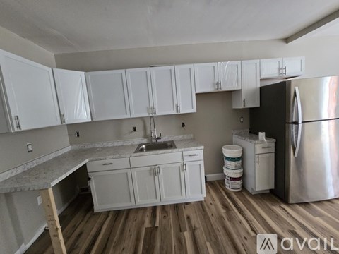 A kitchen with white cabinets and a stainless steel refrigerator.