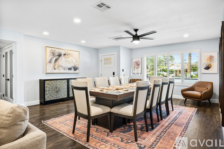 A dining room with a table set for six and a rug on the floor.