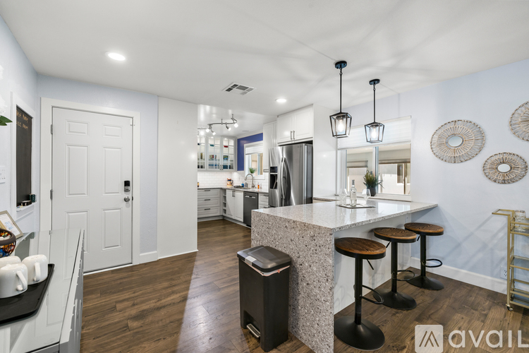 A kitchen with a white door and a bar with stools.