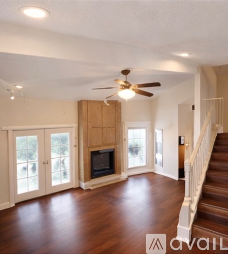 A living room with a wood floor and a staircase.