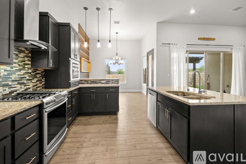 A modern kitchen with black cabinets and a stone backsplash.