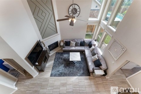 A living room with a grey couch and a fan.