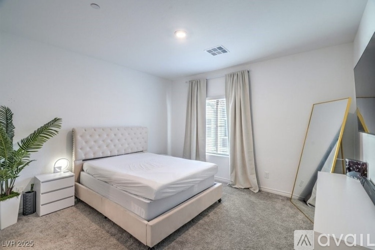 A bedroom with a large bed, a potted plant, and a mirror on the wall.