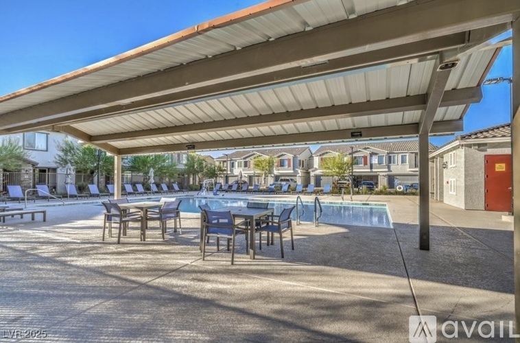 A covered outdoor seating area with a pool table and chairs.