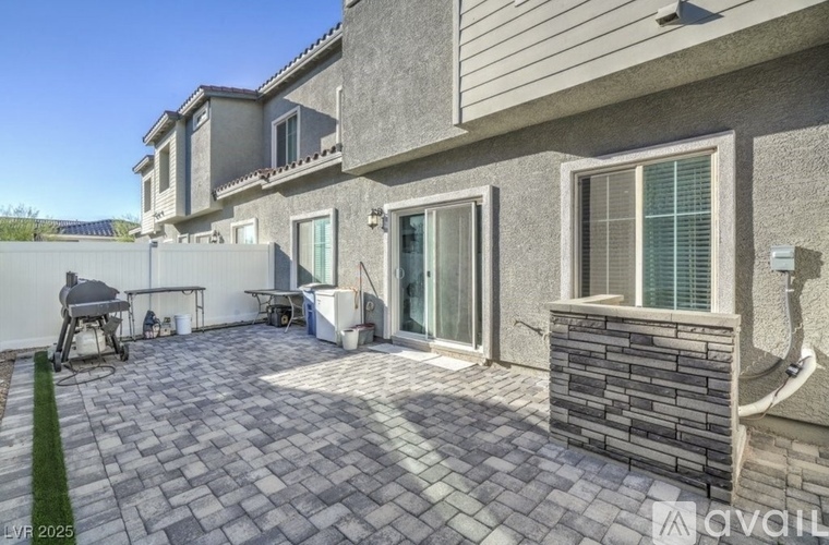 A patio area with a stone wall and a hot tub.
