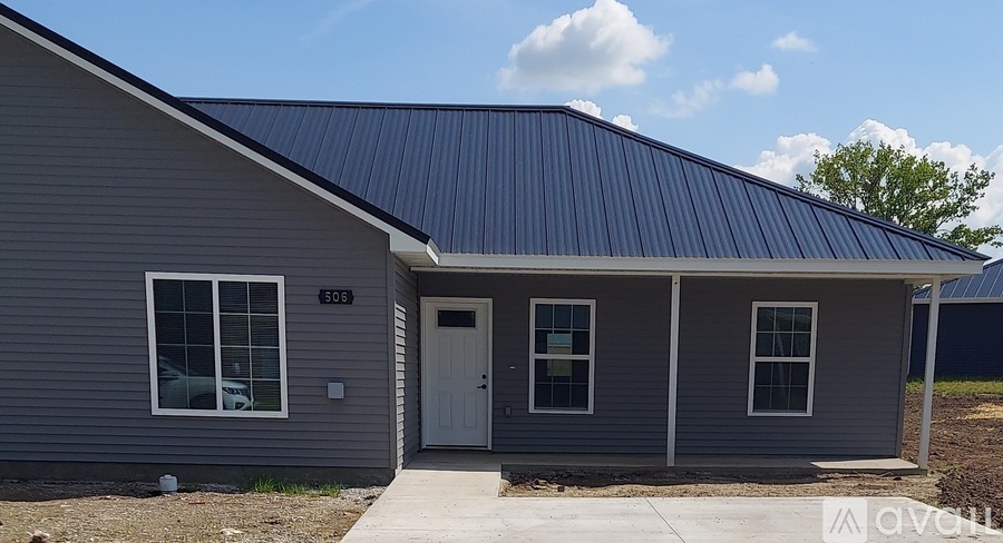 A grey house with a blue roof and a white door.