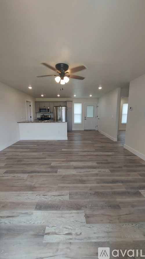 A spacious room with wooden flooring and a ceiling fan.