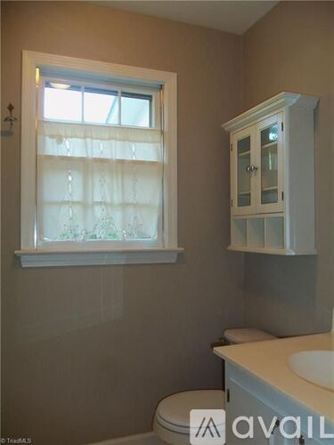 A bathroom with a toilet, sink, and window.