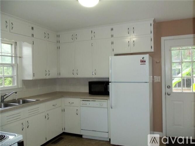 A kitchen with white cabinets and a white fridge.