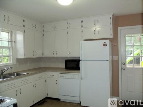 A kitchen with white cabinets and a white fridge.