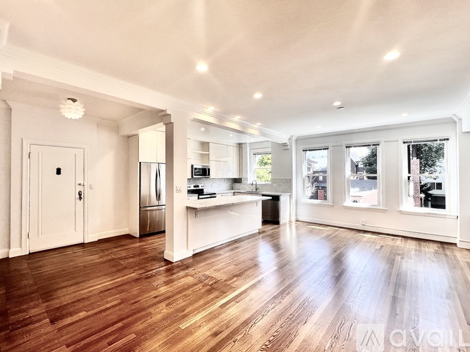 A spacious kitchen with wooden floors and white walls.