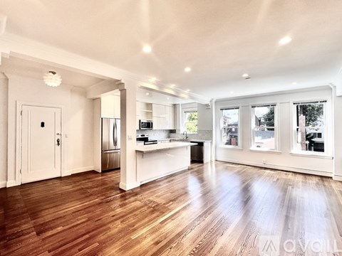 A spacious kitchen with wooden floors and white walls.