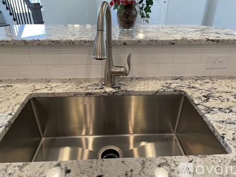 A modern kitchen sink with a chrome faucet and a marble countertop.
