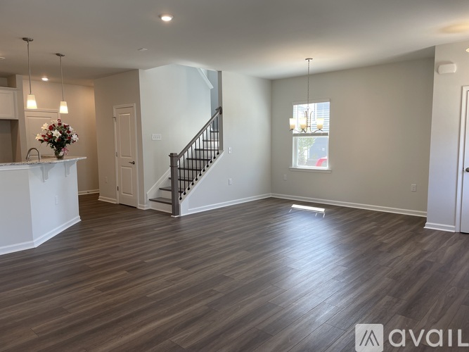 A spacious room with wooden flooring and a staircase.