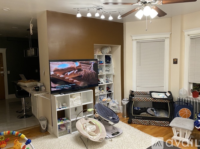 A living room with a television and a baby's crib.