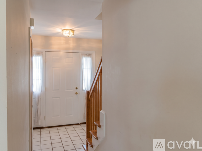 A hallway with a white door and a wooden staircase.