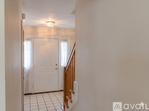 A hallway with a white door and a wooden staircase.