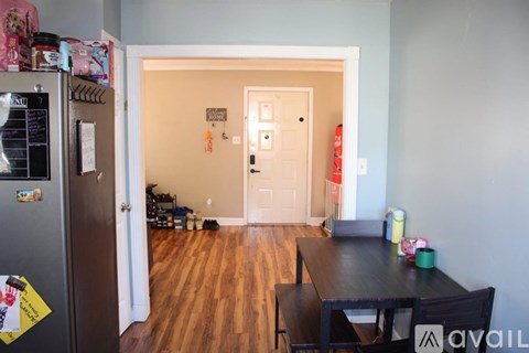 A kitchen with a fridge and a table with chairs in the living room.