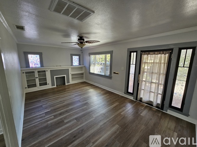 A spacious room with wood flooring and a ceiling fan.