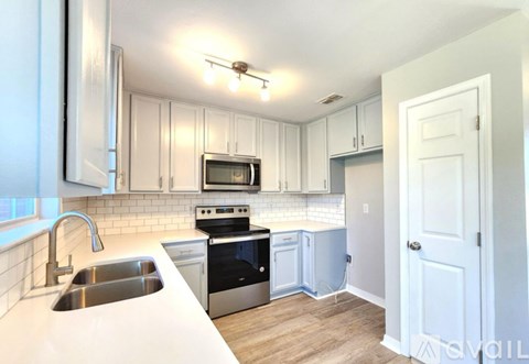 A kitchen with white cabinets and a stainless steel dishwasher.