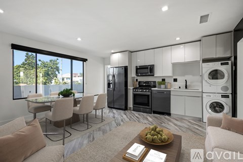 A modern kitchen with a dining table and chairs, and a washing machine and dryer built into the cabinetry.