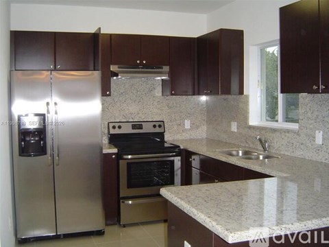 A kitchen with brown cabinets and a granite countertop.